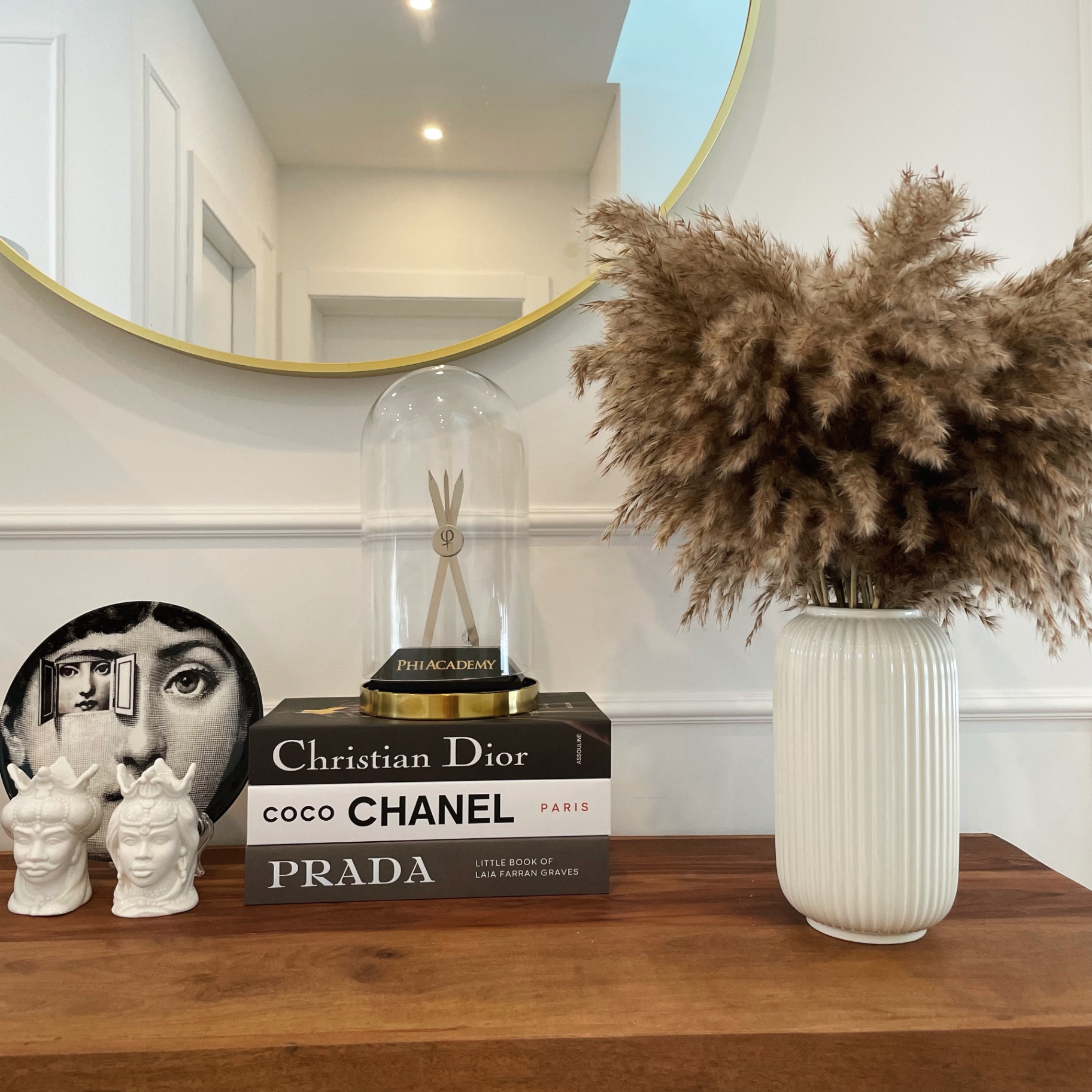 Studio detail — PhiAcademy trophy on Christian Dior, Coco Chanel and Prada books with Fornasetti plate and pampas grass